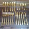 Angled view of full AVD 24 piece gold cutlery set on table