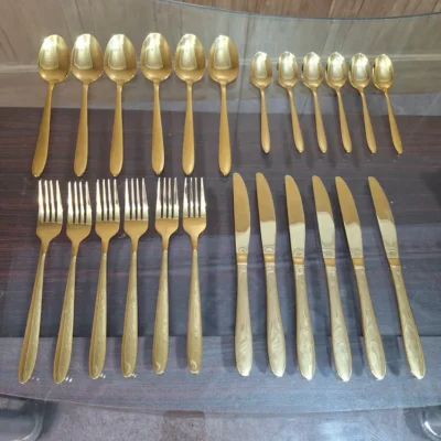 Angled view of full AVD 24 piece gold cutlery set on table